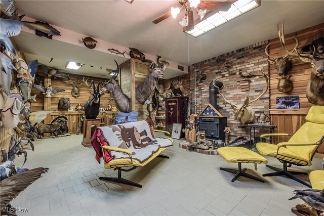5820 Kildare Cir NW, Canton, OH 44718 - sitting room with ceiling fan, a wood stove, tile patterned floors, and wooden walls