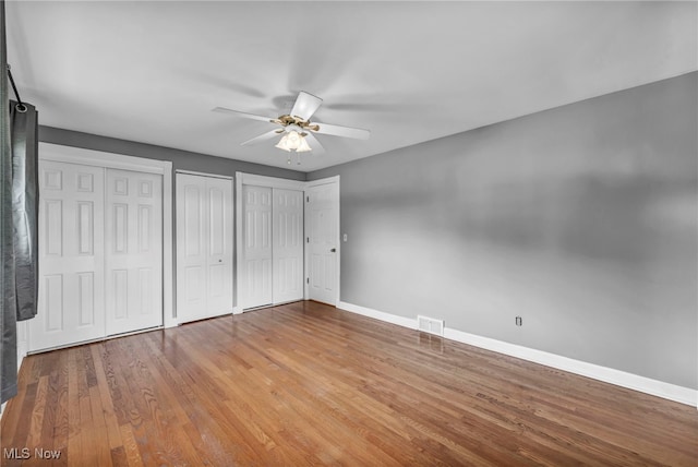 713 Highland Ave, Wadsworth, OH 44281 - unfurnished bedroom with baseboards, two closets, wood finished floors, and ceiling fan