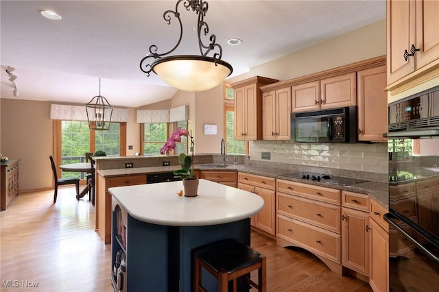 4151 Williamsburg Ct, Medina, OH 44256 - kitchen featuring a peninsula, a kitchen island, black appliances, light wood-style floors, and tasteful backsplash