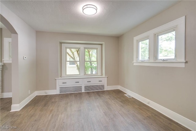 1260 Beardsley St, Akron, OH 44301 - spare room featuring arched walkways, a textured ceiling, wood finished floors, and baseboards