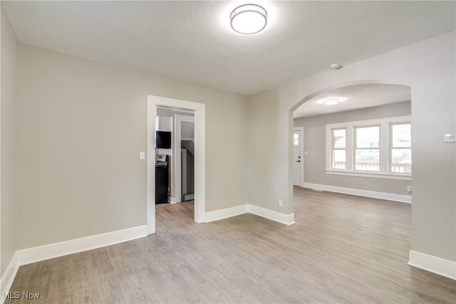 1260 Beardsley St, Akron, OH 44301 - empty room with arched walkways, wood finished floors, baseboards, and a textured ceiling