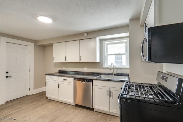 1260 Beardsley St, Akron, OH 44301 - kitchen featuring stainless steel appliances, a sink, dark countertops, white cabinets, and a textured ceiling