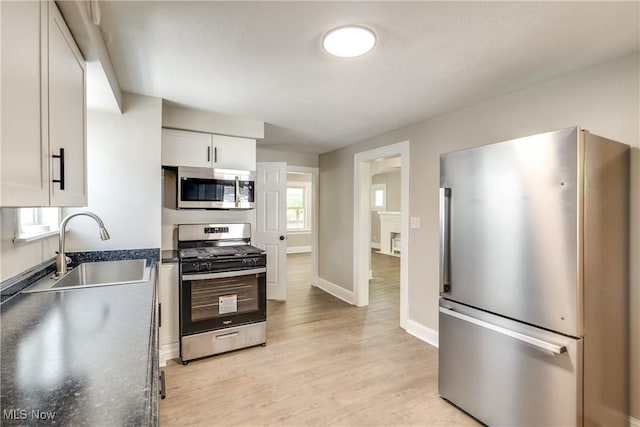 1260 Beardsley St, Akron, OH 44301 - kitchen with appliances with stainless steel finishes, a sink, light wood finished floors, dark countertops, and white cabinetry