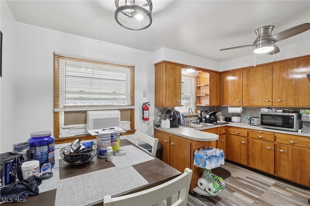 20800 Wilmore Ave, Euclid, OH 44123 - kitchen featuring stainless steel microwave, a sink, light countertops, light wood-type flooring, and brown cabinets