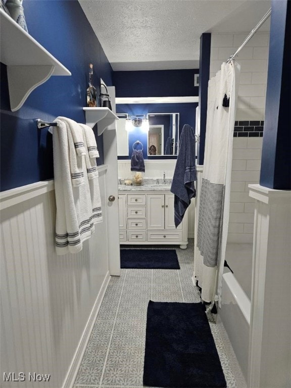 110 Olson Spur, Munroe Falls, OH 44262 - bathroom with vanity, shower / tub combo, a textured ceiling, and wainscoting