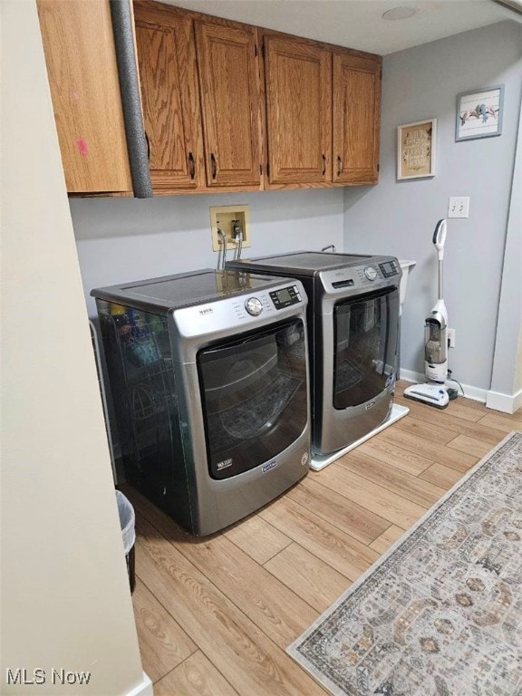 110 Olson Spur, Munroe Falls, OH 44262 - laundry room featuring independent washer and dryer, light wood-style flooring, cabinet space, and baseboards