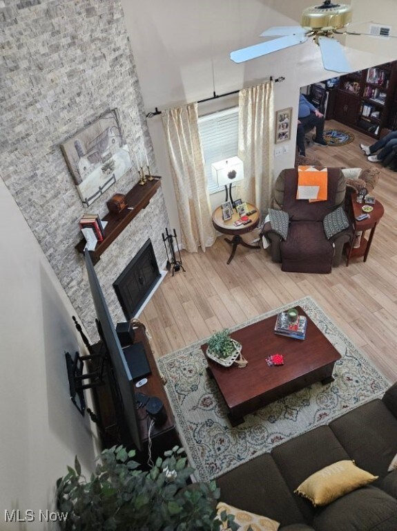 110 Olson Spur, Munroe Falls, OH 44262 - living room featuring wood finished floors, ceiling fan, a stone fireplace, and a towering ceiling