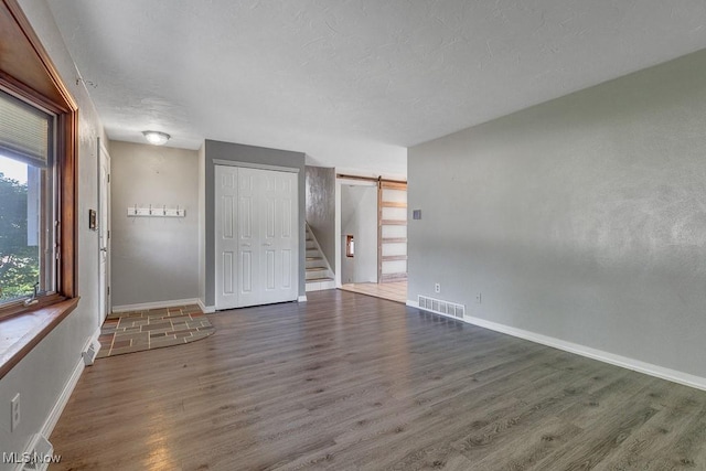 1825 E Skyline Dr, Lorain, OH 44053 - unfurnished room featuring wood finished floors, baseboards, stairs, and a barn door