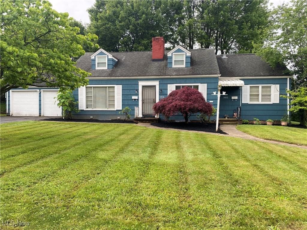 1014 29th St NE, Canton, OH 44714 - cape cod-style house featuring a chimney, asphalt driveway, a front yard, an attached garage, and entry steps