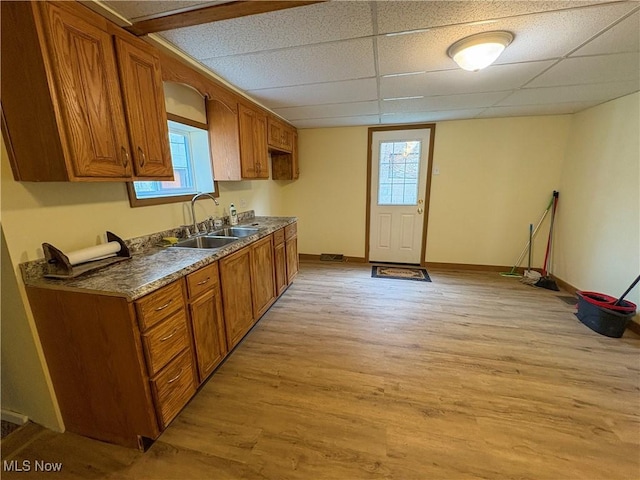 1019 Commerce St, Wellsville, OH 43968 - kitchen with light wood-style flooring, brown cabinetry, a drop ceiling, and dark countertops