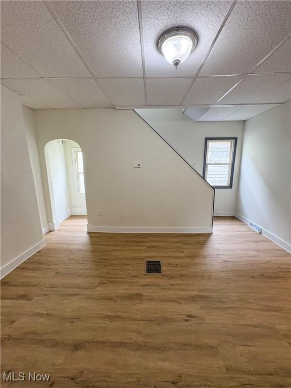 1019 Commerce St, Wellsville, OH 43968 - unfurnished room featuring a drop ceiling, arched walkways, plenty of natural light, and wood finished floors