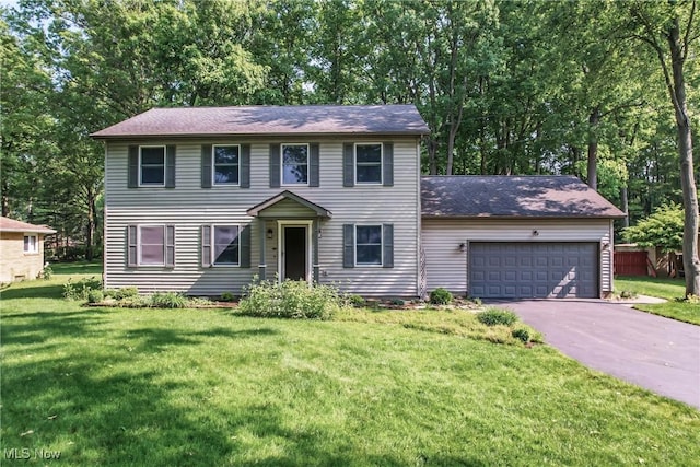 9233 Cain Dr NE, Warren, OH 44484 - colonial inspired home featuring asphalt driveway, a garage, a front yard, and view of wooded area