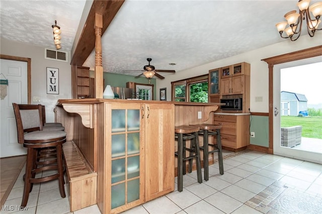 5081 Middle Ridge Rd, Perry, OH 44081 - kitchen featuring black microwave, a kitchen breakfast bar, freestanding refrigerator, light tile patterned floors, and a textured ceiling