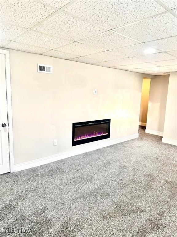 1389 Diagonal Rd, Akron, OH 44320 - unfurnished living room featuring a drop ceiling, a glass covered fireplace, carpet flooring, and baseboards
