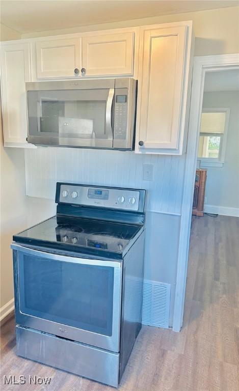 1389 Diagonal Rd, Akron, OH 44320 - kitchen with stainless steel appliances, wood finished floors, white cabinets, and baseboards