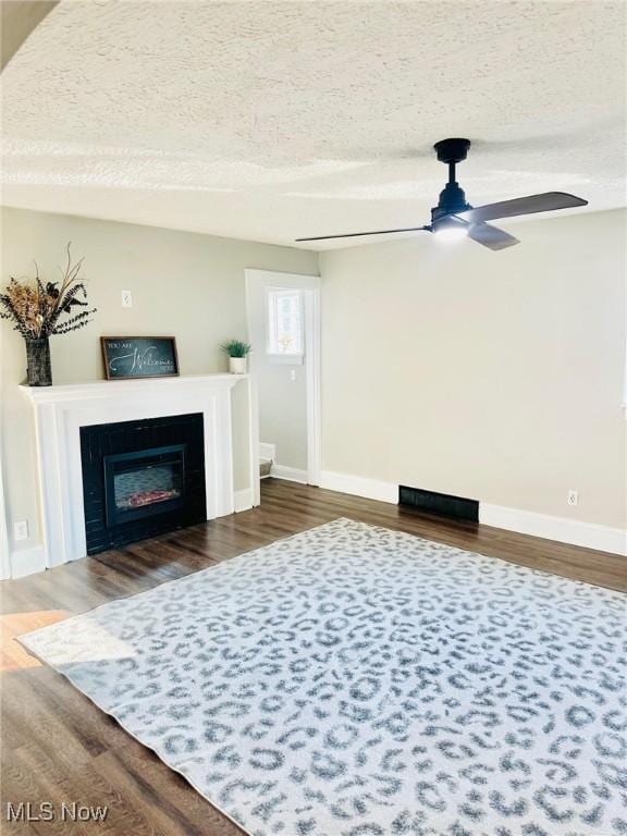 1389 Diagonal Rd, Akron, OH 44320 - living area with a textured ceiling, baseboards, dark wood-style flooring, ceiling fan, and a glass covered fireplace