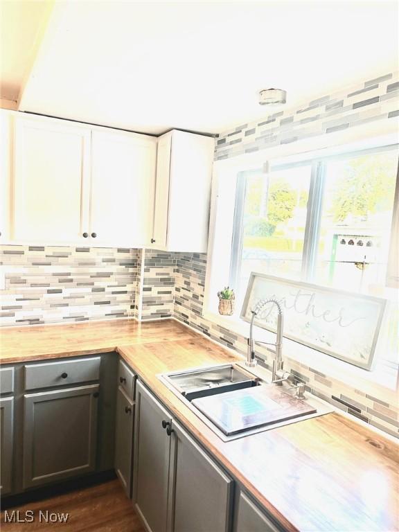 1389 Diagonal Rd, Akron, OH 44320 - kitchen with butcher block counters, backsplash, a sink, and white cabinetry