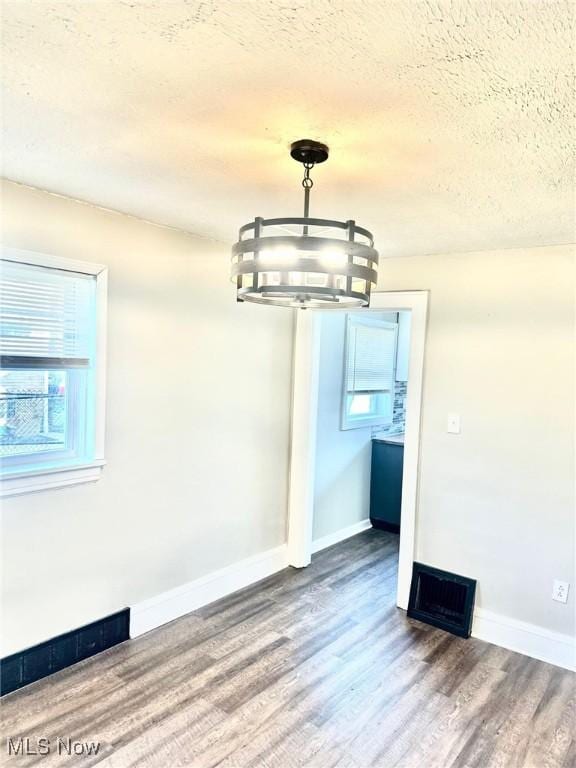 1389 Diagonal Rd, Akron, OH 44320 - unfurnished dining area with a textured ceiling, wood finished floors, a chandelier, and plenty of natural light