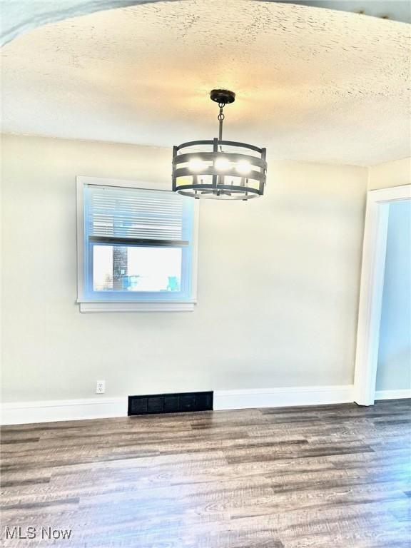 1389 Diagonal Rd, Akron, OH 44320 - unfurnished dining area featuring a chandelier, baseboards, wood finished floors, and a textured ceiling