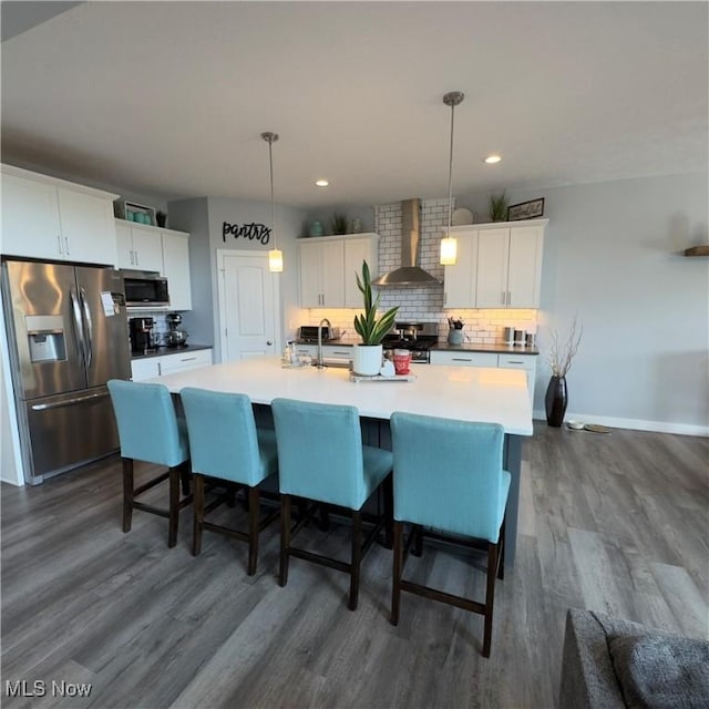 8224 Lilly Ln, Concord, OH 44077 - kitchen with stainless steel appliances, wall chimney range hood, dark wood-style flooring, a center island with sink, and decorative backsplash
