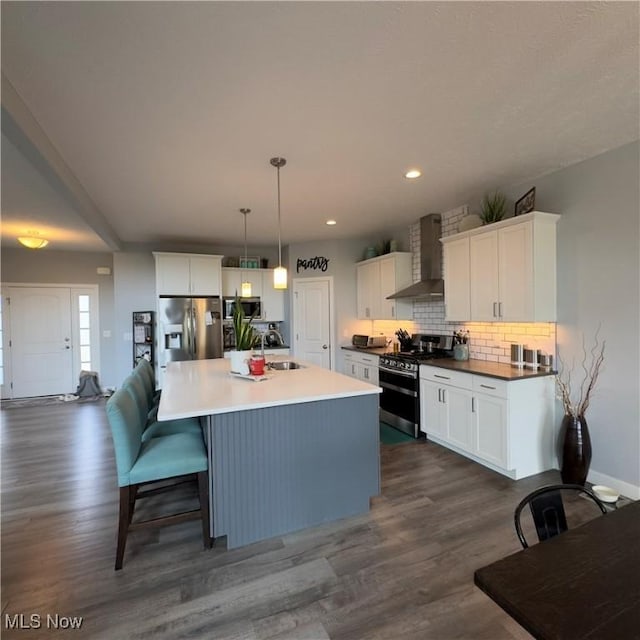 8224 Lilly Ln, Concord, OH 44077 - kitchen featuring wall chimney range hood, stainless steel appliances, a sink, dark wood finished floors, and recessed lighting