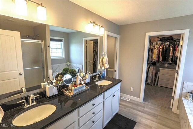 8224 Lilly Ln, Concord, OH 44077 - full bath featuring a stall shower, wood finished floors, double vanity, a garden tub, and a walk in closet