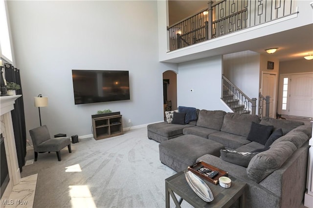 8224 Lilly Ln, Concord, OH 44077 - carpeted living room featuring arched walkways, stairs, a high ceiling, a high end fireplace, and baseboards