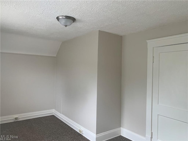 3961 E 53rd St, Newburgh Heights, OH 44105 - empty room featuring dark colored carpet, a textured ceiling, baseboards, and vaulted ceiling
