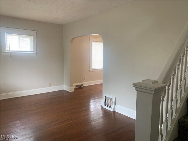 3961 E 53rd St, Newburgh Heights, OH 44105 - unfurnished room with arched walkways, dark wood-type flooring, a textured ceiling, and stairway