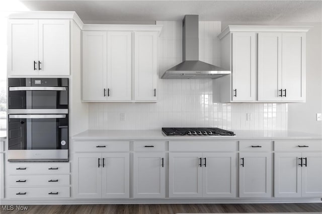 3730 Overlook Ct, Akron, OH 44333 - kitchen featuring wall chimney exhaust hood, gas stovetop, double oven, tasteful backsplash, and white cabinets
