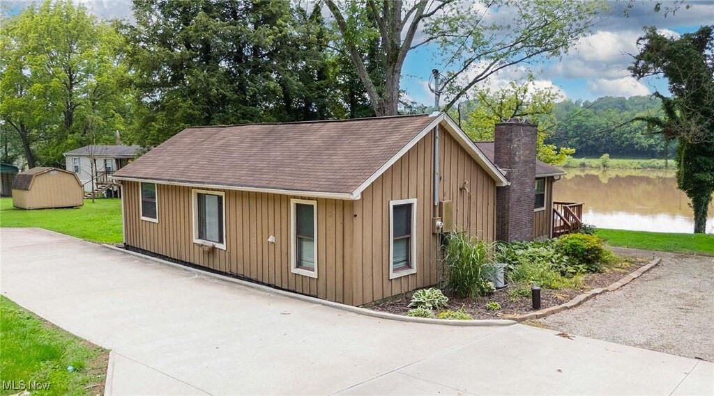 15225 State Route 60, Lowell, OH 45744 - view of front of house with board and batten siding, a front lawn, a shingled roof, and a chimney