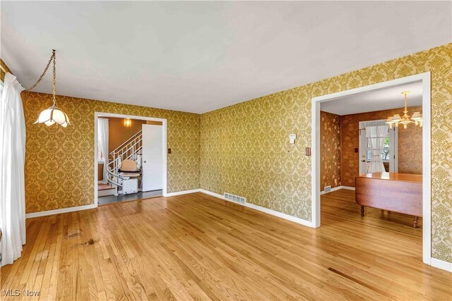 1783 Maywood Rd, South Euclid, OH 44121 - unfurnished room featuring hardwood / wood-style flooring, stairway, a chandelier, wallpapered walls, and baseboards