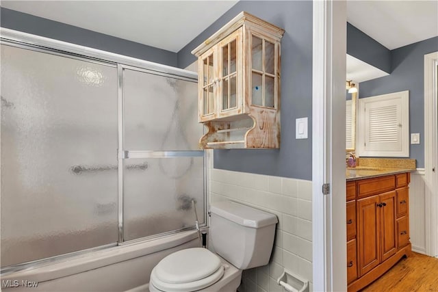 1783 Maywood Rd, South Euclid, OH 44121 - full bath featuring toilet, bath / shower combo with glass door, vanity, wood finished floors, and a wainscoted wall