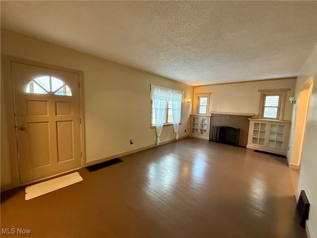 3427 Elm St, Weirton, WV 26062 - unfurnished living room with a textured ceiling, a brick fireplace, and wood finished floors