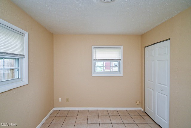 2312 Midway Ave NE, Canton, OH 44705 - unfurnished bedroom featuring light tile patterned flooring, a closet, and baseboards