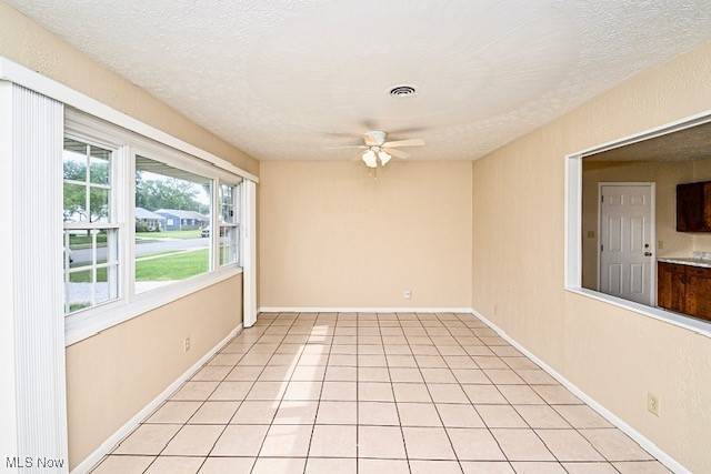 2312 Midway Ave NE, Canton, OH 44705 - empty room featuring ceiling fan, a textured ceiling, light tile patterned floors, and baseboards