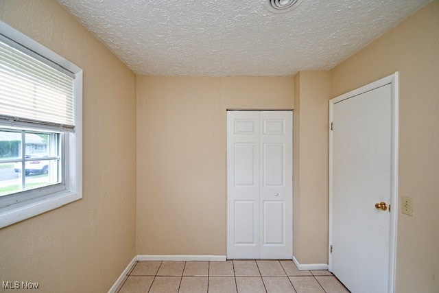 2312 Midway Ave NE, Canton, OH 44705 - unfurnished bedroom with a closet, a textured ceiling, light tile patterned floors, and baseboards