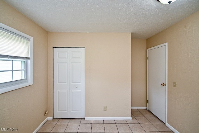 2312 Midway Ave NE, Canton, OH 44705 - unfurnished bedroom with a closet, light tile patterned floors, a textured ceiling, and baseboards