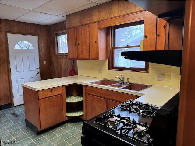615 Noah Ave, Akron, OH 44320 - kitchen featuring black range with gas cooktop, a peninsula, brown cabinets, a sink, and wooden walls