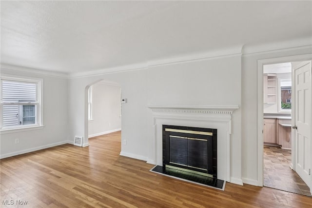 21601 Roberts Ave, Euclid, OH 44123 - unfurnished living room featuring wood finished floors, arched walkways, a glass covered fireplace, and baseboards