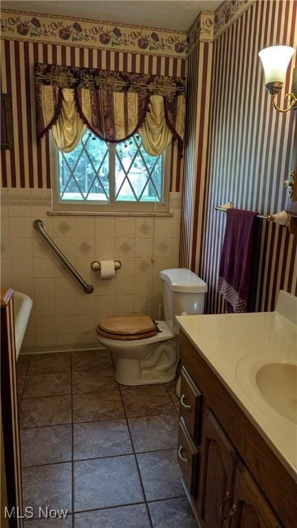 2615 Orchard Park St NW, Canton, OH 44718 - bathroom featuring wallpapered walls, vanity, tile walls, a wainscoted wall, and toilet
