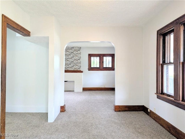 623 Cole Ave, Akron, OH 44301 - spare room with carpet floors, arched walkways, a fireplace, a textured ceiling, and baseboards