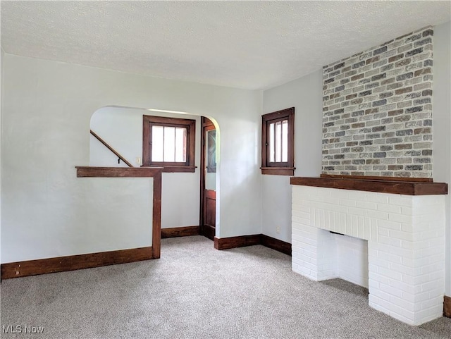 623 Cole Ave, Akron, OH 44301 - unfurnished living room featuring carpet floors, healthy amount of natural light, a textured ceiling, baseboards, and arched walkways