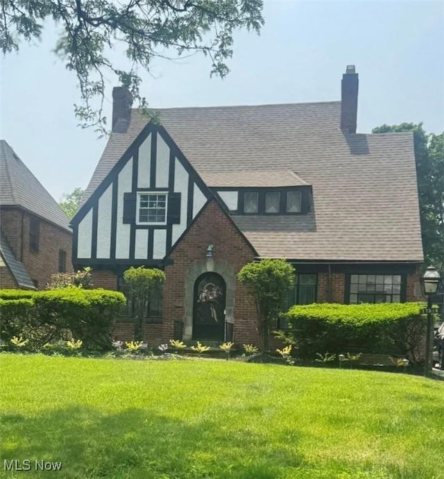 17314 Lomond Blvd, Shaker Heights, OH 44120 - tudor home with brick siding, a front yard, a chimney, and a shingled roof