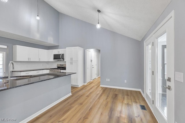 8000 Lake Rd, Seville, OH 44273 - kitchen with stainless steel appliances, a sink, white cabinets, dark stone countertops, and high vaulted ceiling