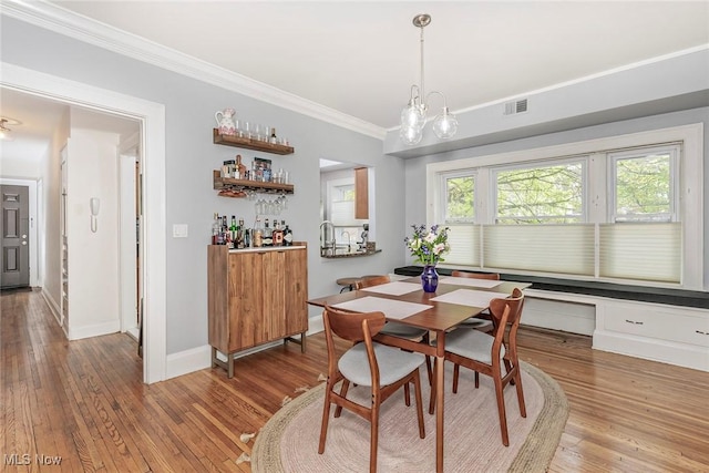 2725 Hampshire Rd Unit 2, Cleveland Heights, OH 44106 - dining space with crown molding, hardwood / wood-style floors, a dry bar, baseboards, and a chandelier