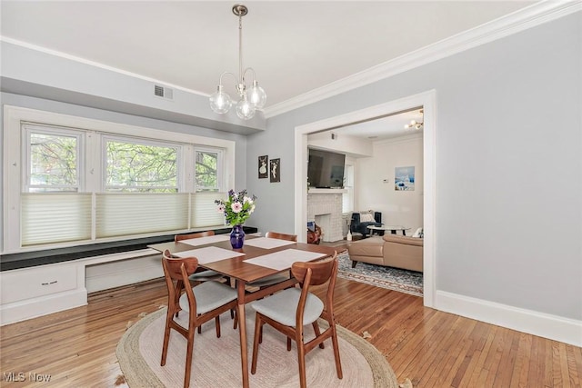 2725 Hampshire Rd Unit 2, Cleveland Heights, OH 44106 - dining area featuring ornamental molding, a chandelier, a brick fireplace, light wood-style floors, and baseboards