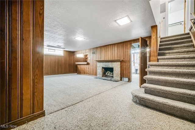 1540 S Belvoir Blvd, South Euclid, OH 44121 - unfurnished living room with a textured ceiling, stairs, a fireplace, and wood walls