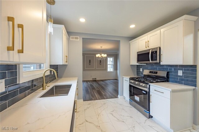17607 Scottsdale Blvd, Shaker Heights, OH 44120 - kitchen featuring appliances with stainless steel finishes, a sink, a chandelier, baseboards, and light stone counters