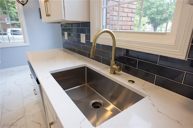 17607 Scottsdale Blvd, Shaker Heights, OH 44120 - kitchen view of a sink, decorative backsplash, light stone countertops, and white cabinetry